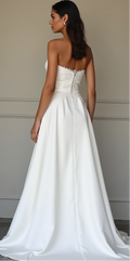 Chic satin A-line bridal gown with a strapless lace bodice, fitted waist, and long flowing train – a luxurious and sophisticated wedding dress choice. | فستان زفاف أنيق بقصة A-Line مع كورسيه مزين بالدانتيل وذيل طويل راقٍ لمظهر زفاف مميز | Vestido de novia con falda en A, corsé de encaje y una elegante cola larga – sofisticado y moderno. | Robe de mariée fluide avec corset en dentelle et traîne en satin – idéale pour une mariée élégante et raffinée.